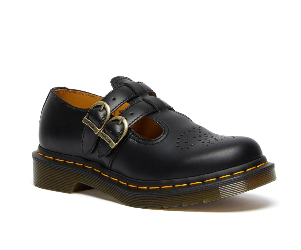A black leather Dr. Martens mary jane shoe with brass buckles.