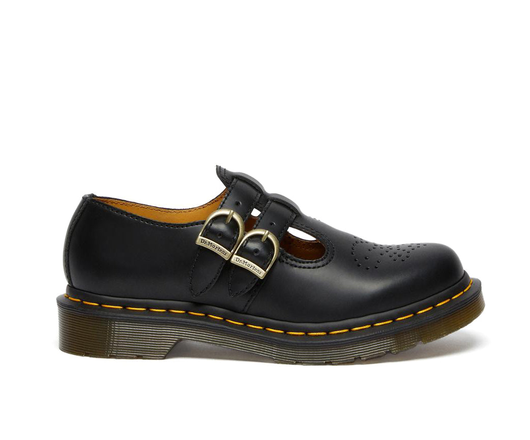 A black leather Dr. Martens mary jane shoe with brass buckles.