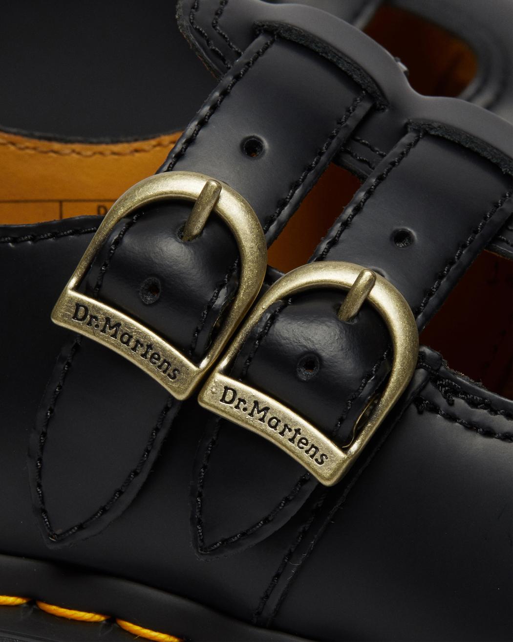A black leather Dr. Martens mary jane shoe with brass buckles.