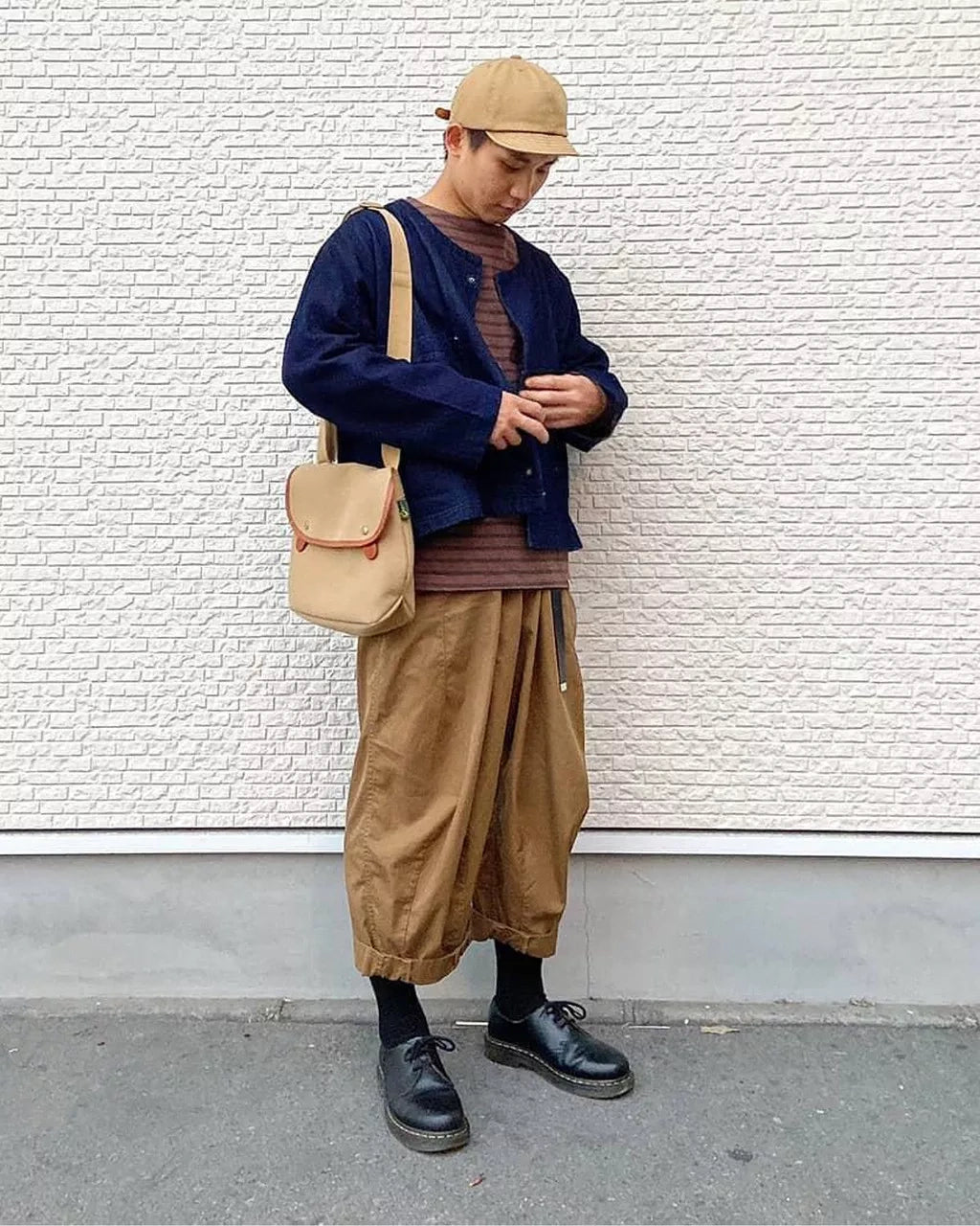 A model wearing a pair of low cut black leather oxford shoe from Dr. Martens.