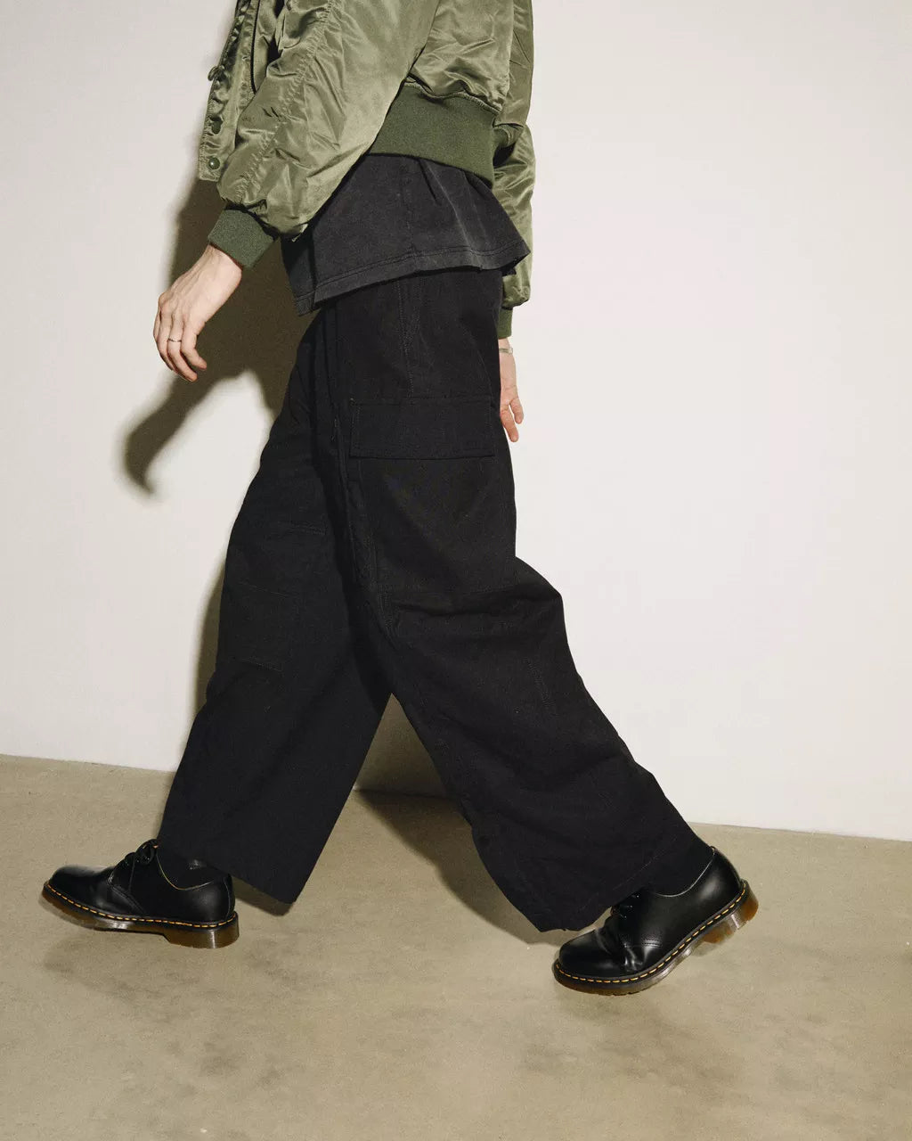 A model wearing a pair of low cut black leather oxford shoe from Dr. Martens.