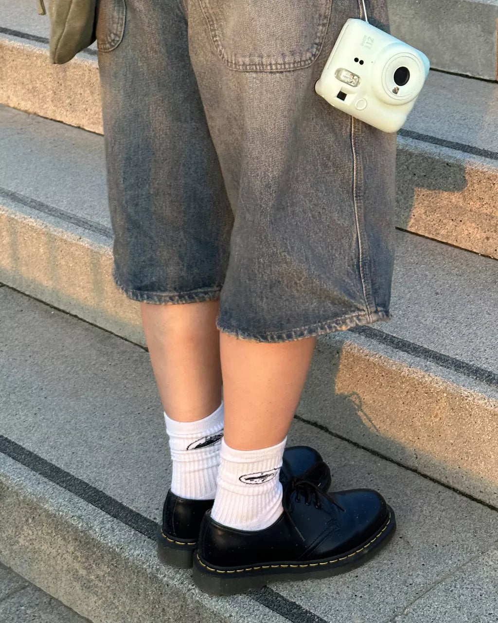 A model wearing a pair of low cut black leather oxford shoe from Dr. Martens.